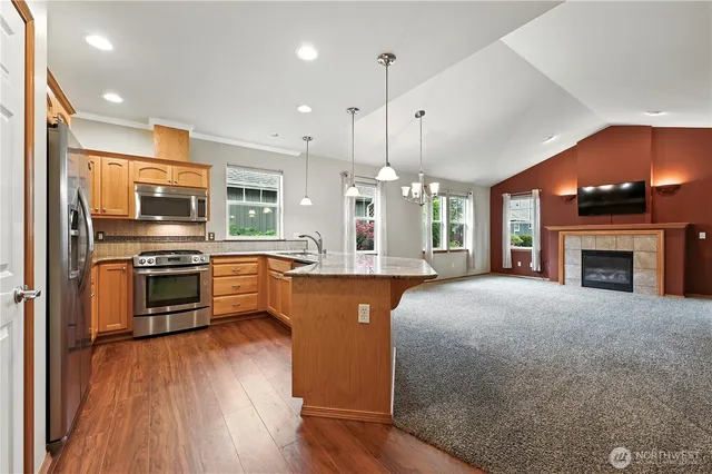 a large kitchen with stainless steel appliances granite countertop a stove a sink dishwasher a refrigerator white cabinets and wooden floor