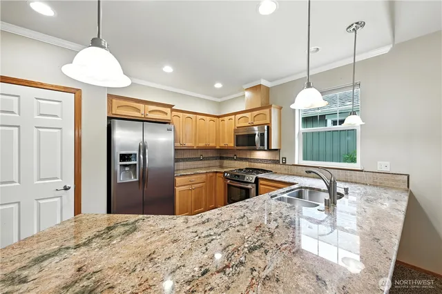 a kitchen with stainless steel appliances granite countertop a sink refrigerator and cabinets