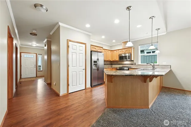 a view of kitchen with stainless steel appliances granite countertop cabinets and wooden floor