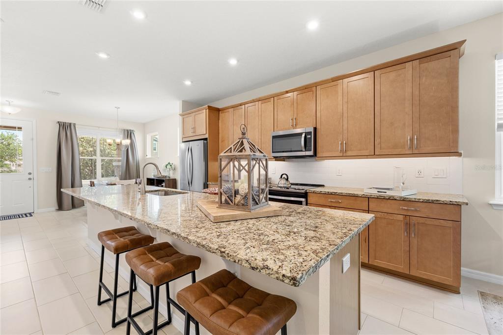 16716 Wingspread Loop Winter Garden, FL 34787 - Photo 9 of 56 a kitchen with kitchen island granite countertop wooden cabinets a stove a sink and a granite counter tops