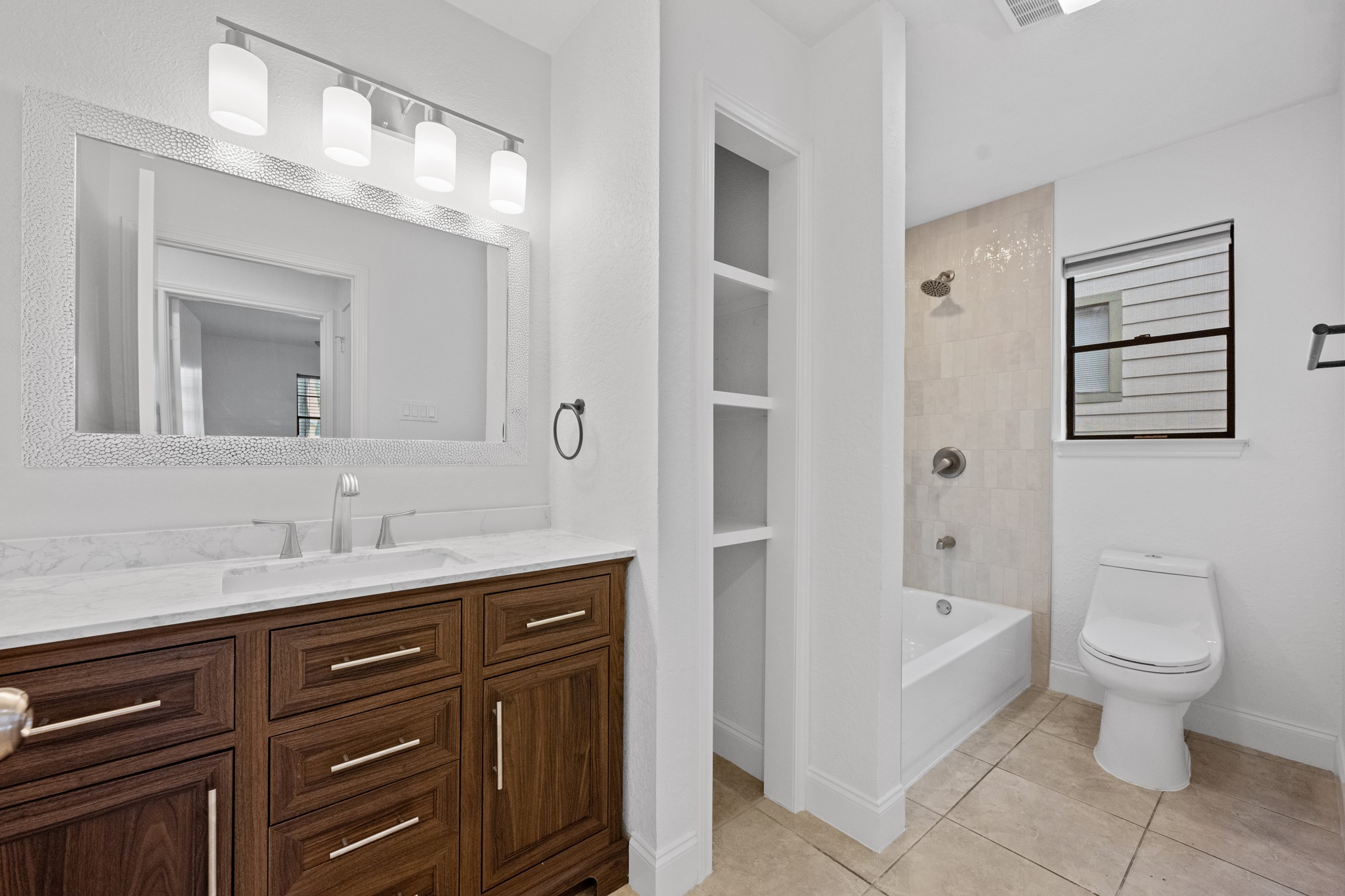 7210 Smokey Hill Road Austin, TX 78736 - Photo 21 of 29 A well-appointed bathroom features a dark wood vanity, modern fixtures, and a tiled shower-over-tub combination.