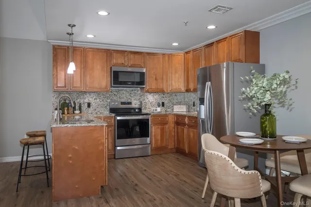 a kitchen with stainless steel appliances a refrigerator a stove a sink a dining table and chairs