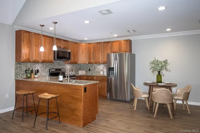 a kitchen with stainless steel appliances granite countertop a refrigerator a stove top oven a sink dishwasher and wooden floor