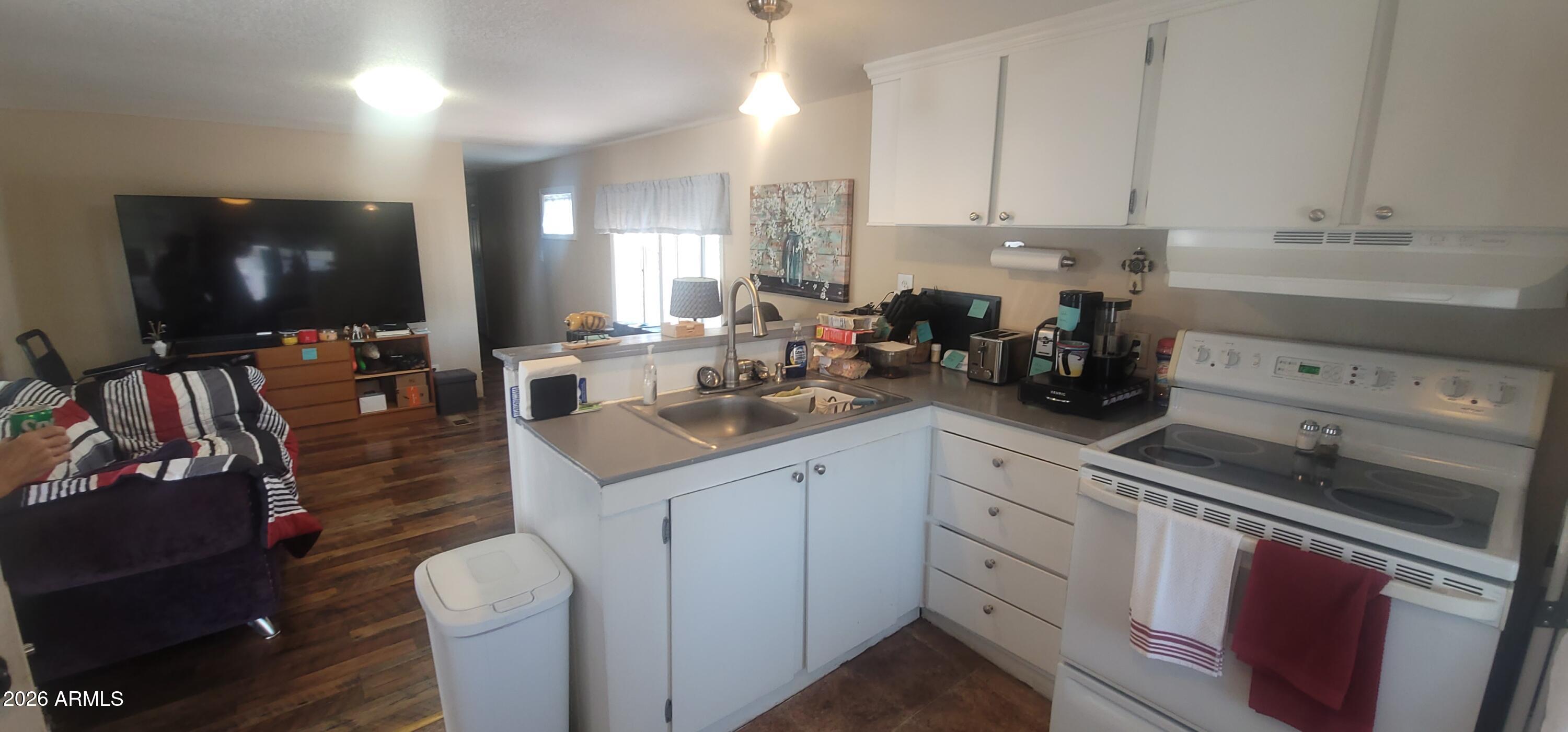 800 West Apache Trail, Unit 24 Apache Junction, AZ 85120 - Photo 5 of 11 a kitchen with a sink dishwasher and white cabinets with wooden floor