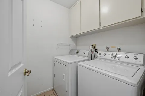 a view of a white house with a big yard and potted plants