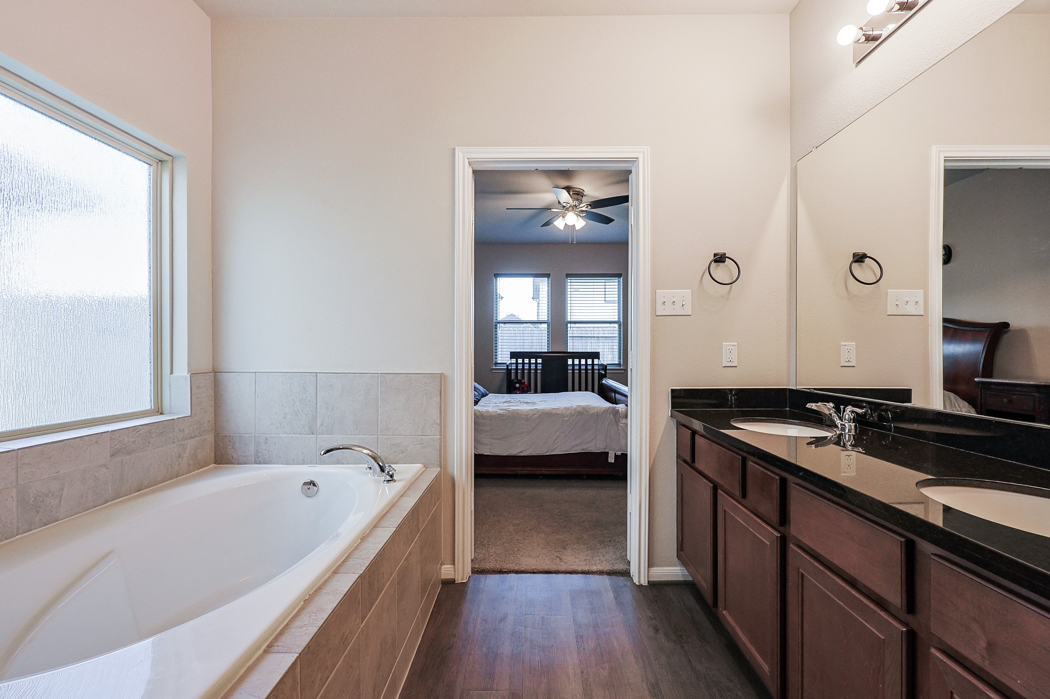 10423 Rochester Hls Lane Tomball, TX 77375 - Photo 21 of 36 The vanity is topped with a sleek, dark polished counter and dual chrome fixtures beneath a massive, wall-to-wall mirror that amplifies the room's bright feel.