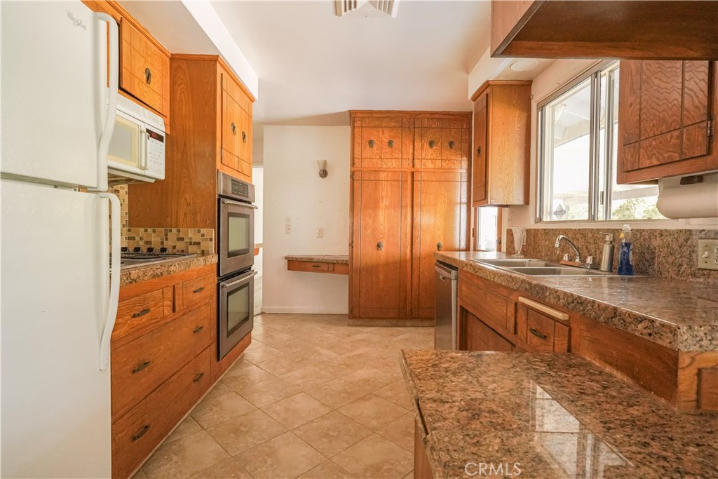 56320 Tamarisk Court Yucca Valley, CA 92284 - Photo 15 of 46 a kitchen with granite countertop a refrigerator and cabinets