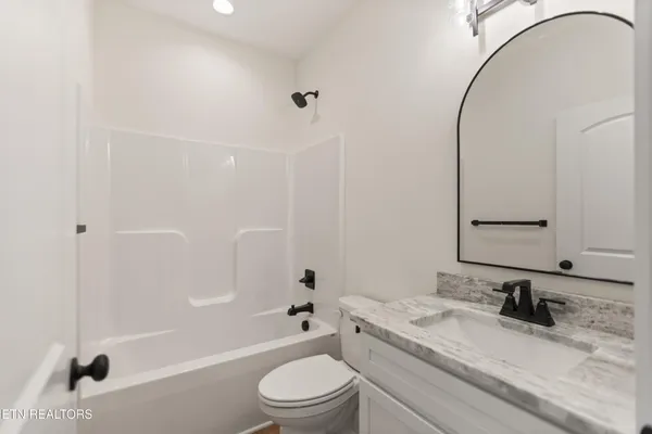 a bathroom with a granite countertop sink toilet a mirror and shower