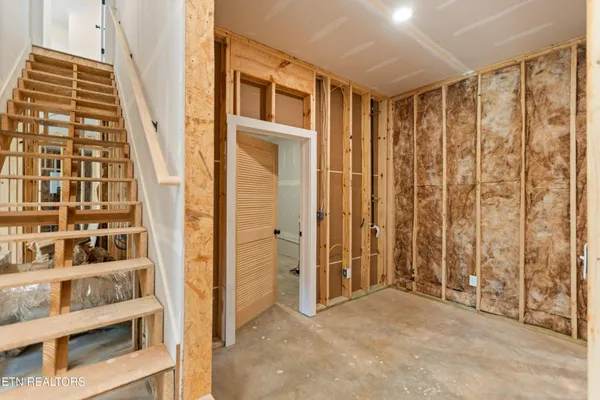 a view of an empty room with wooden floor and stairs