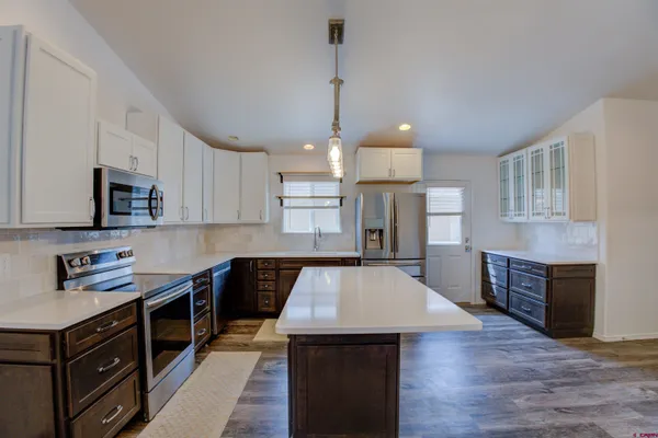 a kitchen with stainless steel appliances granite countertop a kitchen island hardwood floor sink stove dining table and chairs