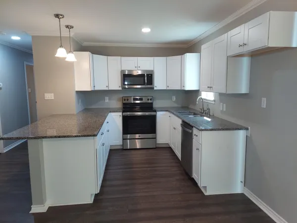 a kitchen with stainless steel appliances granite countertop a sink a stove and a wooden floors