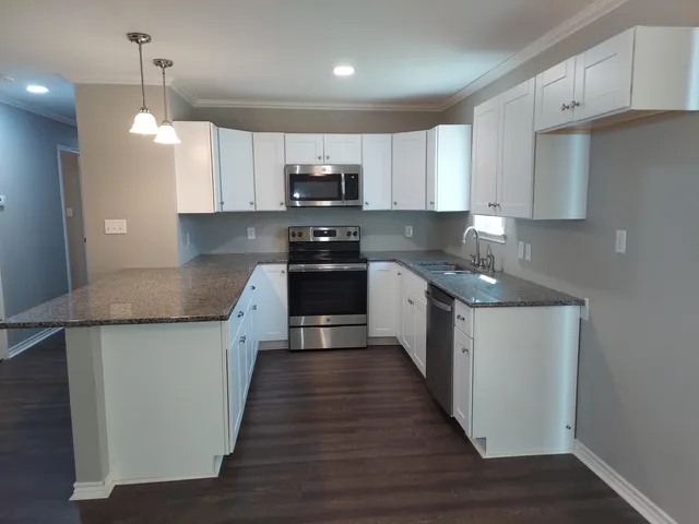a kitchen with stainless steel appliances granite countertop a sink a stove and a wooden floors