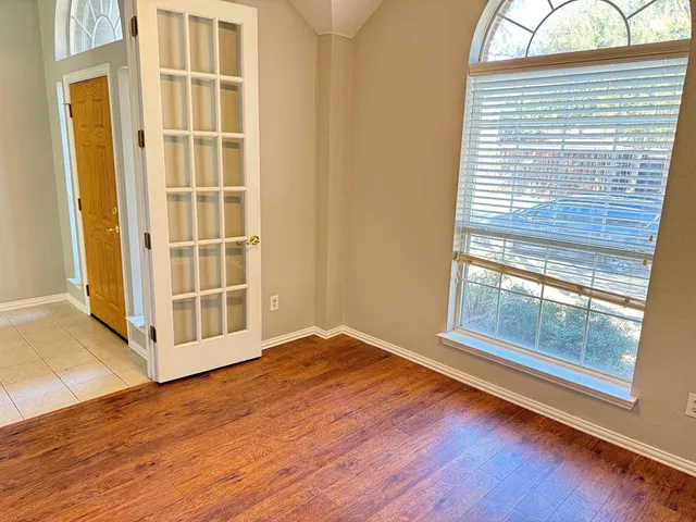 a view of an empty room with a window and wooden floor