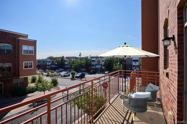 a view of a patio with couches table and chairs under an umbrella with a small yard