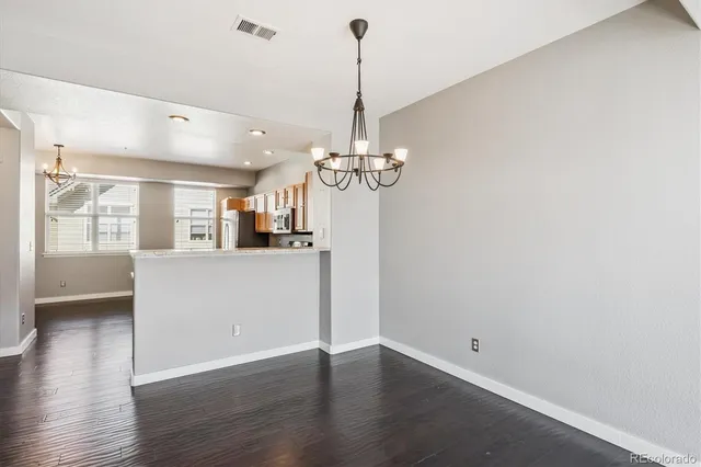 a view of a room with wooden floor chandelier and windows