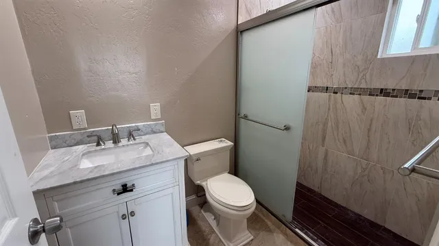 a bathroom with a granite countertop sink toilet and a mirror