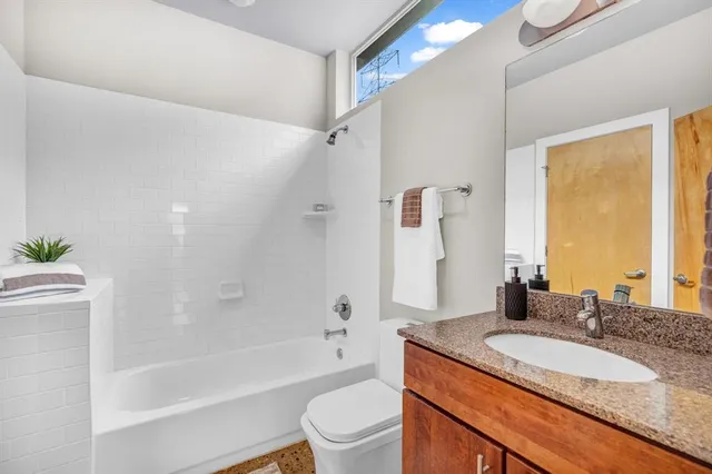 a bathroom with a granite countertop sink toilet tub and shower