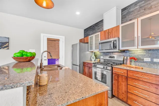 a kitchen with stainless steel appliances granite countertop a sink a stove and a wooden cabinets