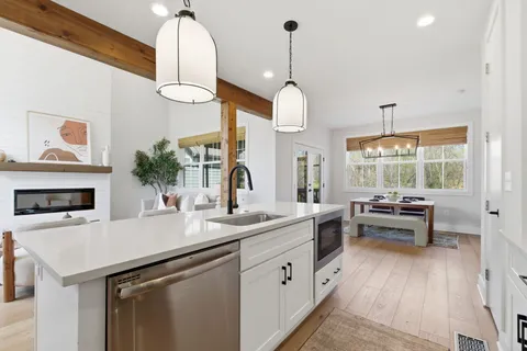 a kitchen with a sink dishwasher a stove and a dining table with wooden floor