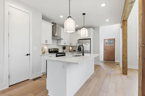 a view of a kitchen with kitchen island a sink stainless steel appliances and cabinets