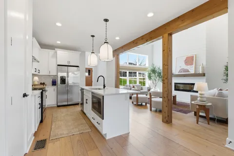 a kitchen with stainless steel appliances kitchen island granite countertop a stove top oven a sink a dining table and chairs with wooden floor