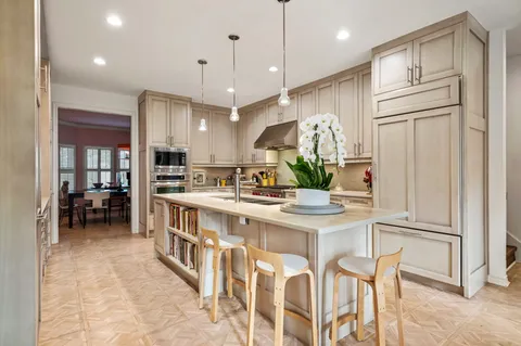 a kitchen with stainless steel appliances kitchen island granite countertop a table chairs and a refrigerator