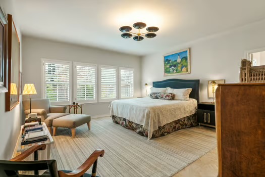 311 Ridgewood Road Austin, TX 78746 - Photo 23 of 38 a bedroom with a bed and a chandelier