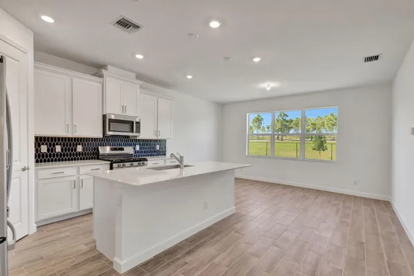 a kitchen with stainless steel appliances a refrigerator a stove top oven a sink and cabinets