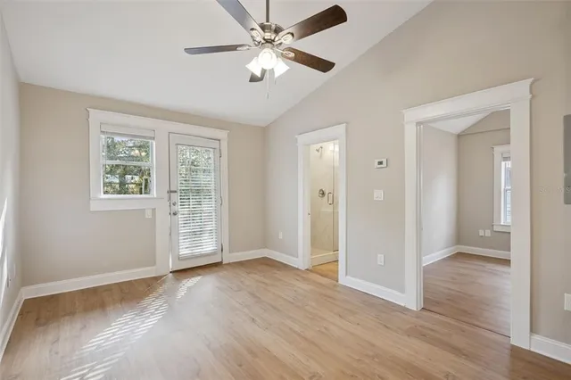 an empty room with wooden floor ceiling fan and windows