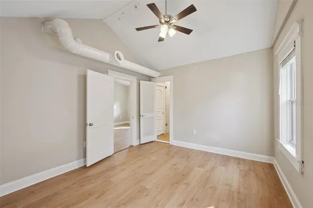a view of empty room with wooden floor and fan