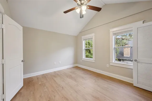 an empty room with wooden floor fan and windows