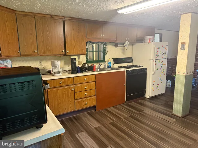 a kitchen with stainless steel appliances granite countertop a refrigerator a sink dishwasher and a stove with wooden cabinets