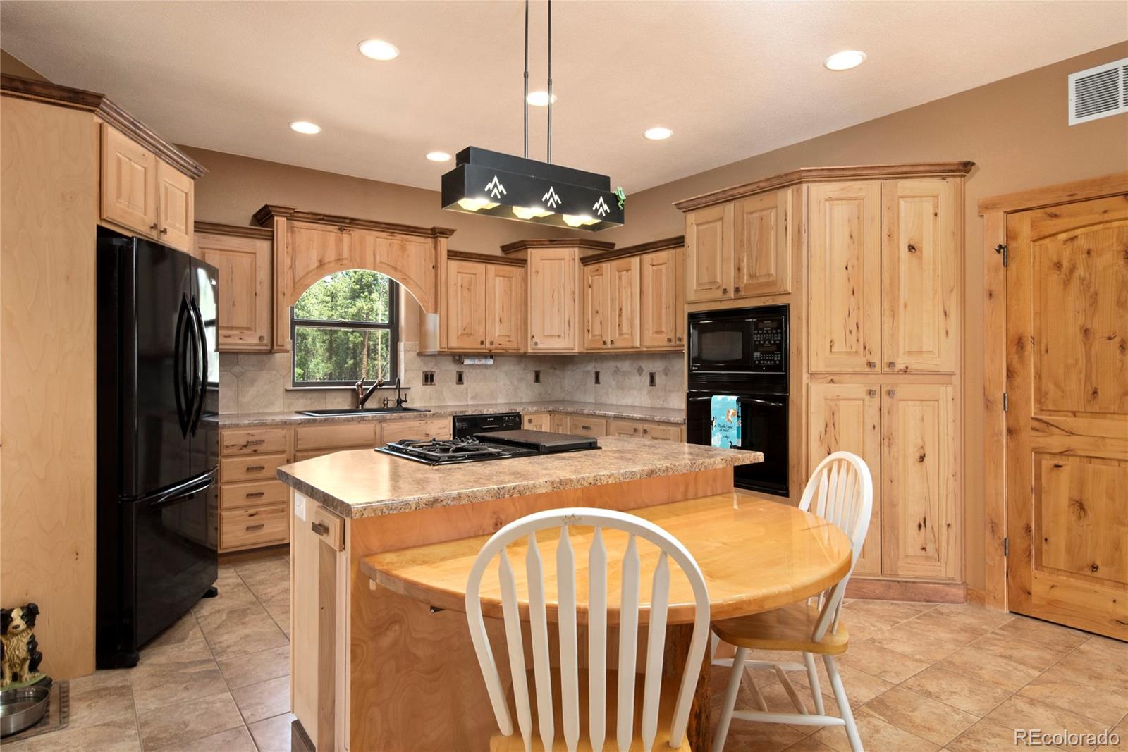 8620 Ridge Road Beulah, CO 81023 - Photo 9 of 34 a kitchen with stainless steel appliances granite countertop a refrigerator a stove a sink a dining table and chairs with wooden floor