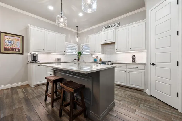 a kitchen with stainless steel appliances kitchen island granite countertop a stove a sink and white cabinets with wooden floor