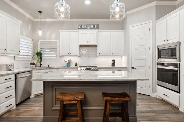 a kitchen with kitchen island granite countertop a sink cabinets and stainless steel appliances