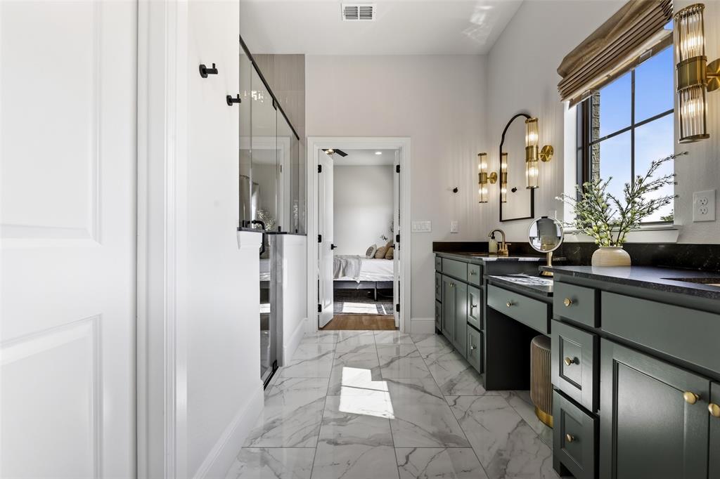 10978 Gregory Road Sanger, TX 76266 - Photo 23 of 40 Spacious bathroom featuring marble-finish flooring, dual vanity with dark cabinetry, dark countertops, and a large window with natural light