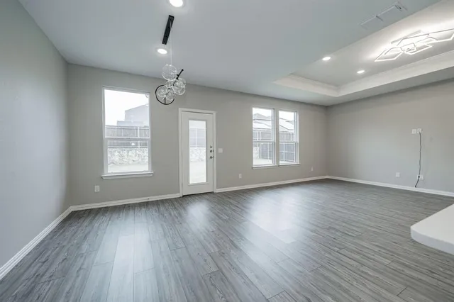 a view of an empty room with wooden floor and fan