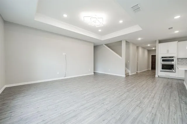 an empty room with wooden floor fireplace and windows