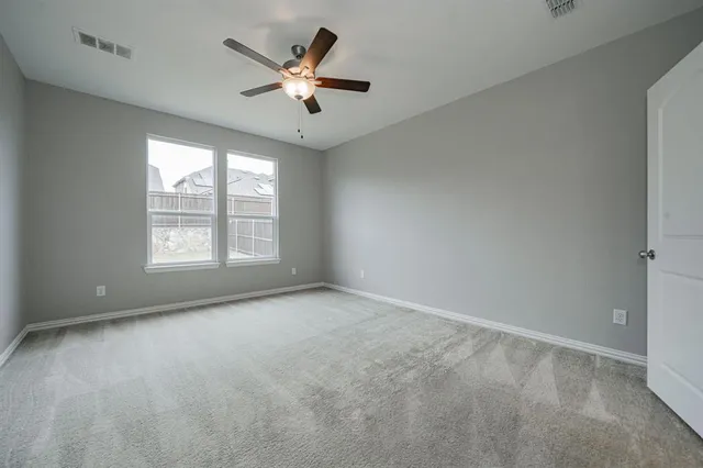 an empty room with chandelier fan and windows