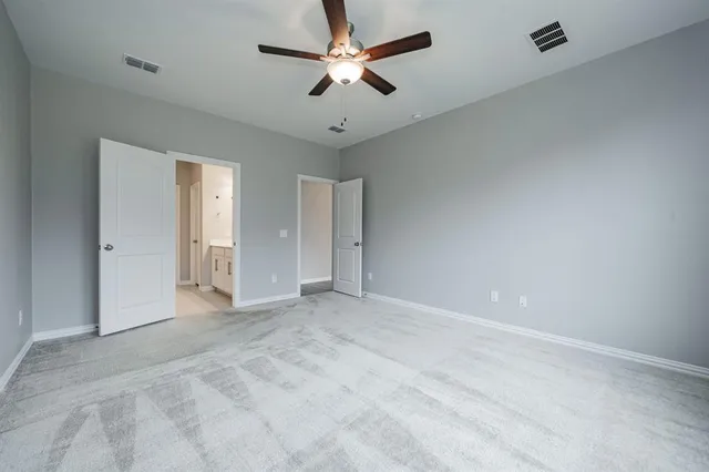 an empty room with chandelier fan and windows