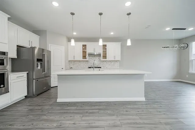 a view of kitchen with granite countertop cabinets and refrigerator