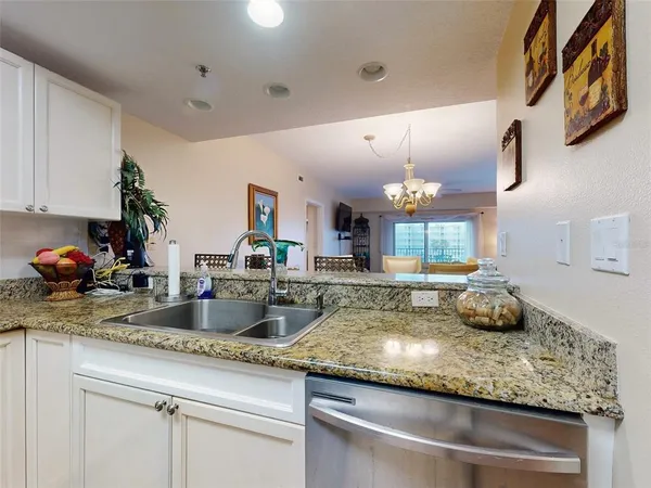 a kitchen with granite countertop white cabinets appliances a sink and a counter space