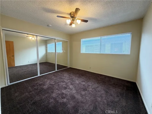 an empty room with closet and a ceiling fan