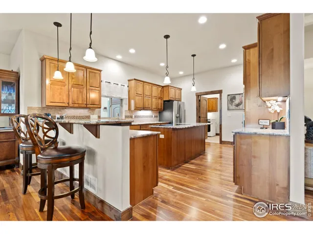 a kitchen with stainless steel appliances kitchen island granite countertop a table chairs and a refrigerator