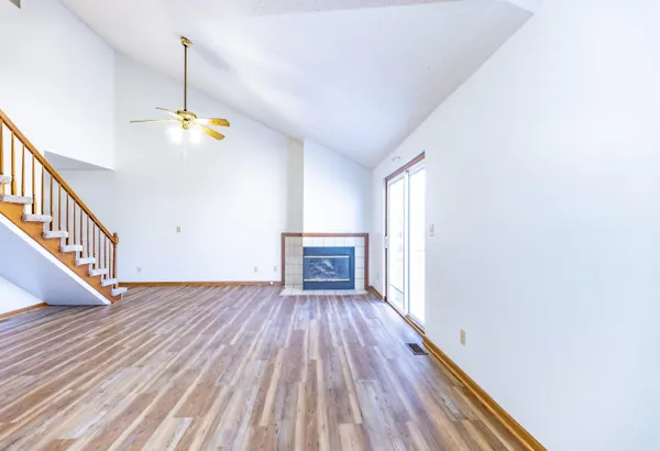a view of an empty room with wooden floor and a chandelier