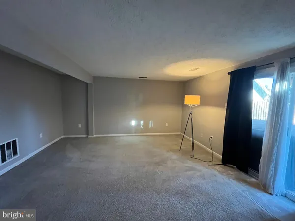 a view of an empty room with fire place and a window