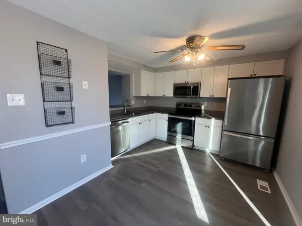 a kitchen with granite countertop a refrigerator stove and sink