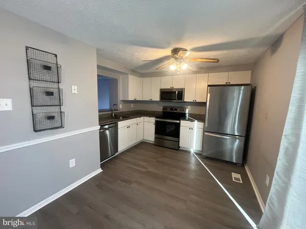 a kitchen with stainless steel appliances a refrigerator a sink a stove top oven a counter space and cabinets