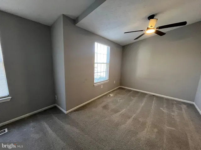 an empty room with windows and fan