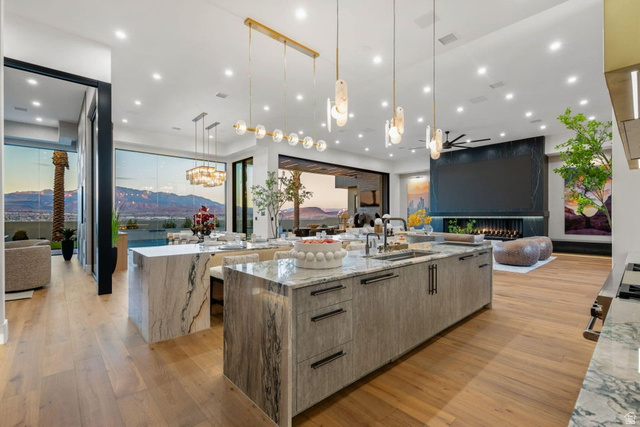 2867 East Granite Way St. George, UT 84790 - Photo 16 of 69 Gourmet kitchen featuring a large waterfall island with integrated sink, wood-finish flooring, recessed lighting, and a modern linear chandelier